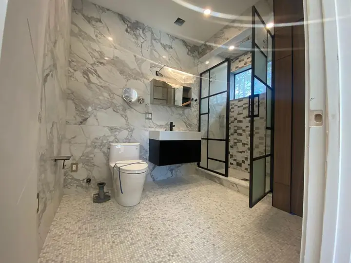 Marble-style bathroom with a pebble mosaic floor and black-framed glass