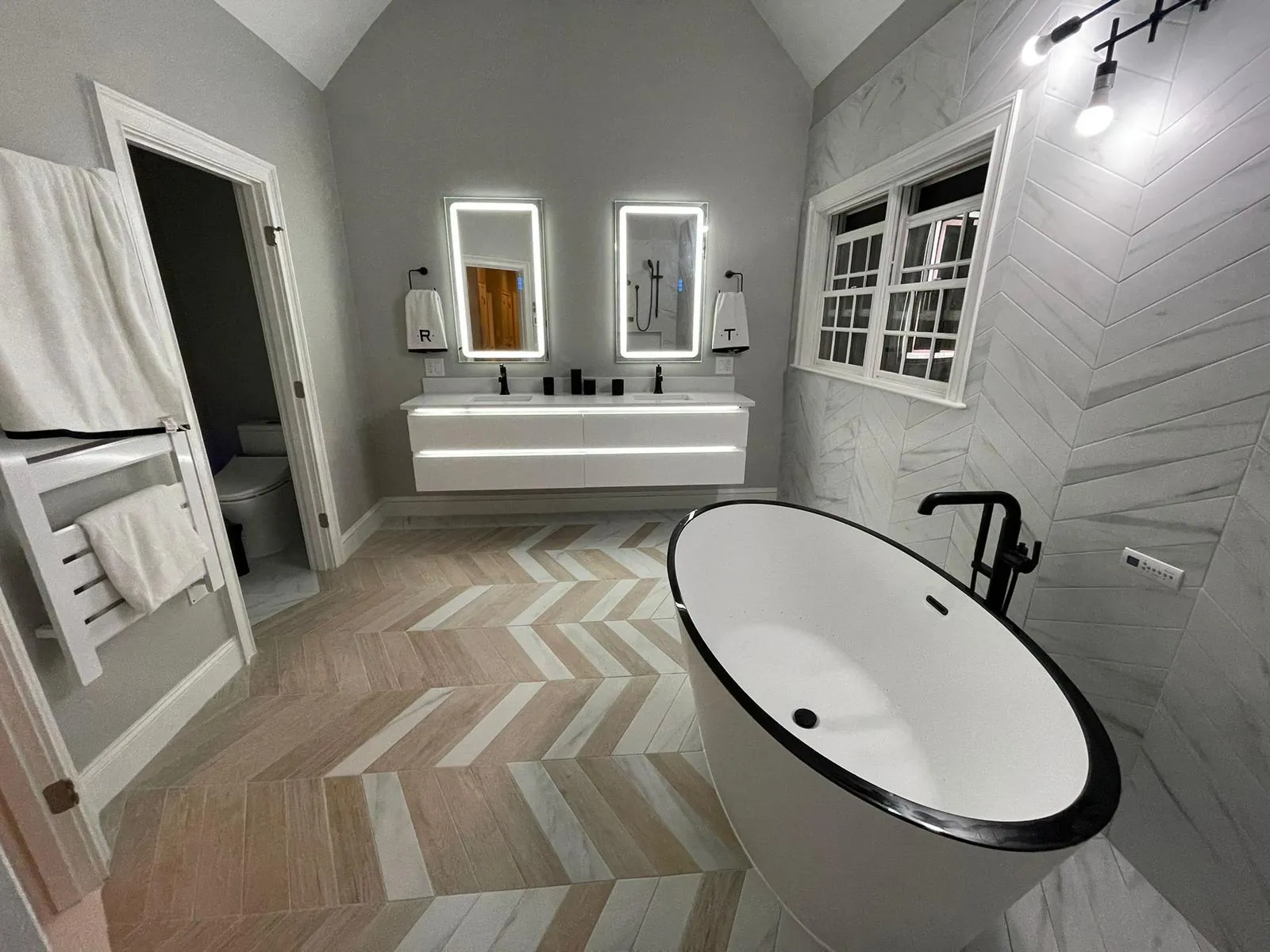Bathroom with a chevron tile floor, floating vanity and freestanding tub