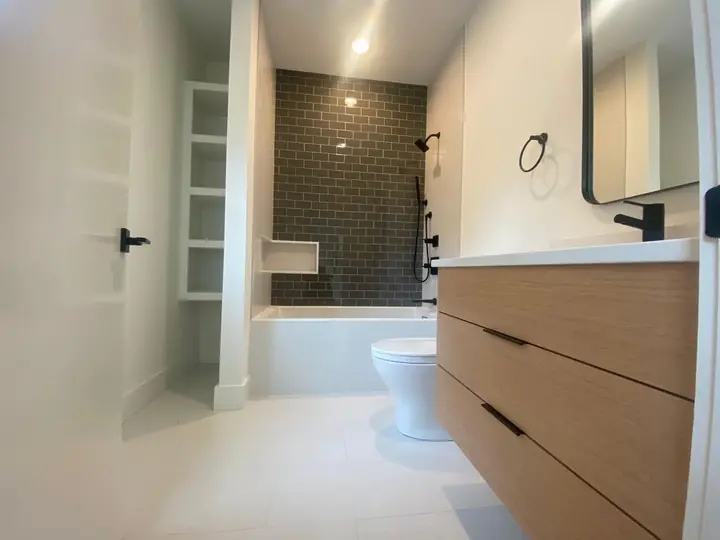Bathroom with a dark tile shower wall and light porcelain floor