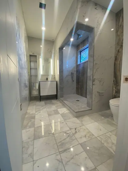 Bathroom with a polished marble-style floor and glass shower