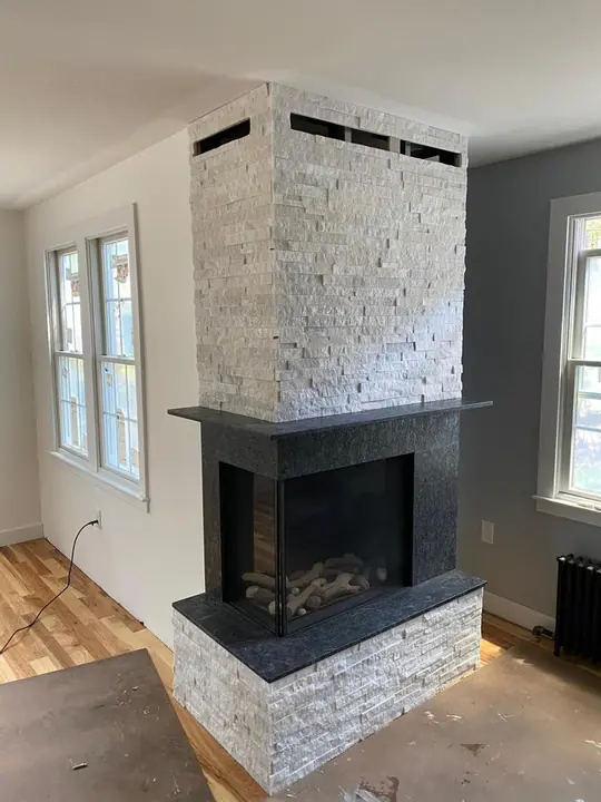 Two-sided fireplace column clad in stacked stone