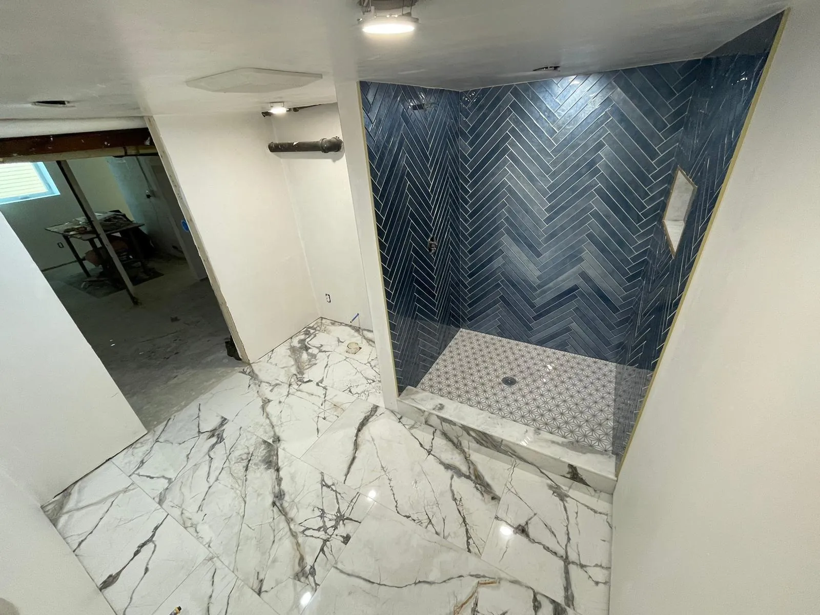 Marble-style floor with a navy herringbone shower wall