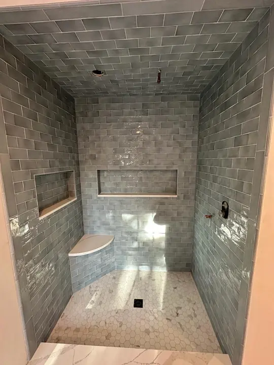 Gray tile shower with a bench and recessed niches