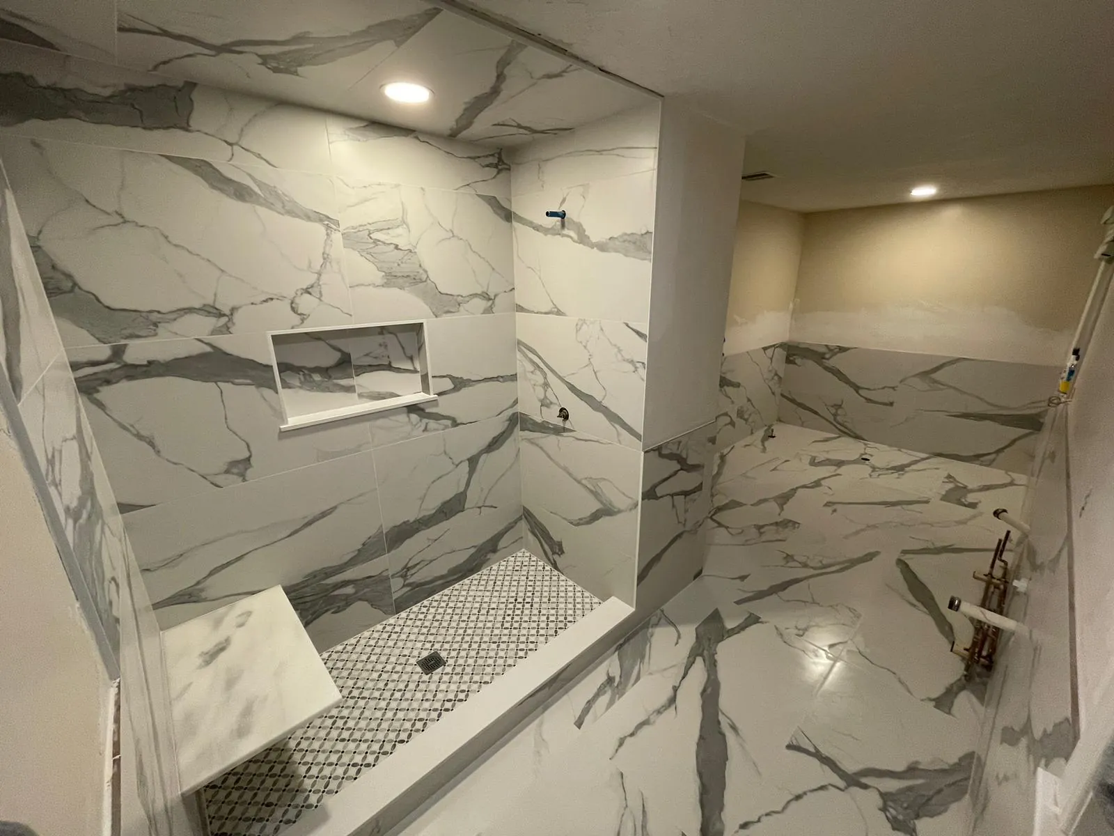 Marble-style shower with a long niche and mosaic floor