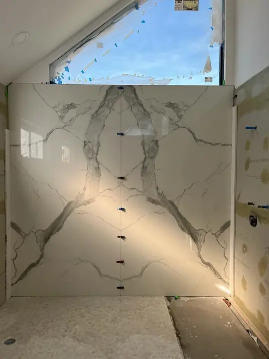 Bookmatched marble-style slab tile on a shower wall